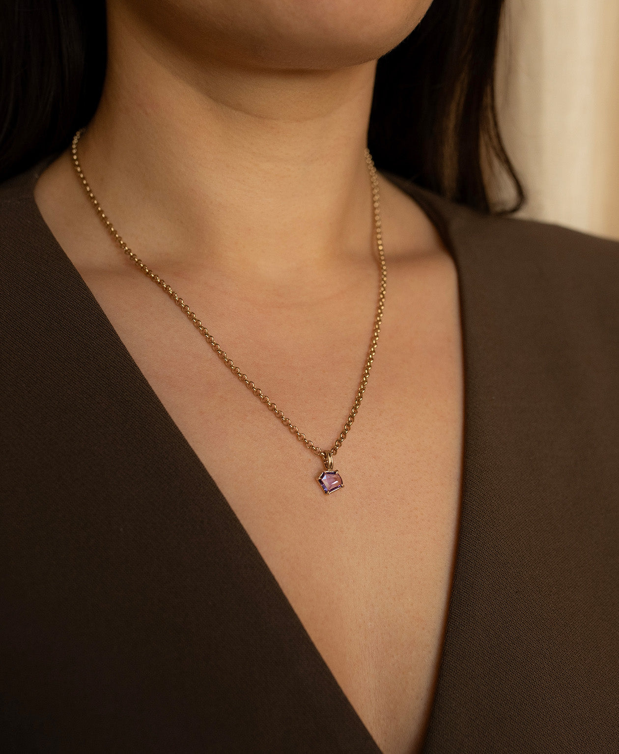 One of a Kind Charm 495 with a portrait cut purple sapphire worn by a model on a belcher chain.