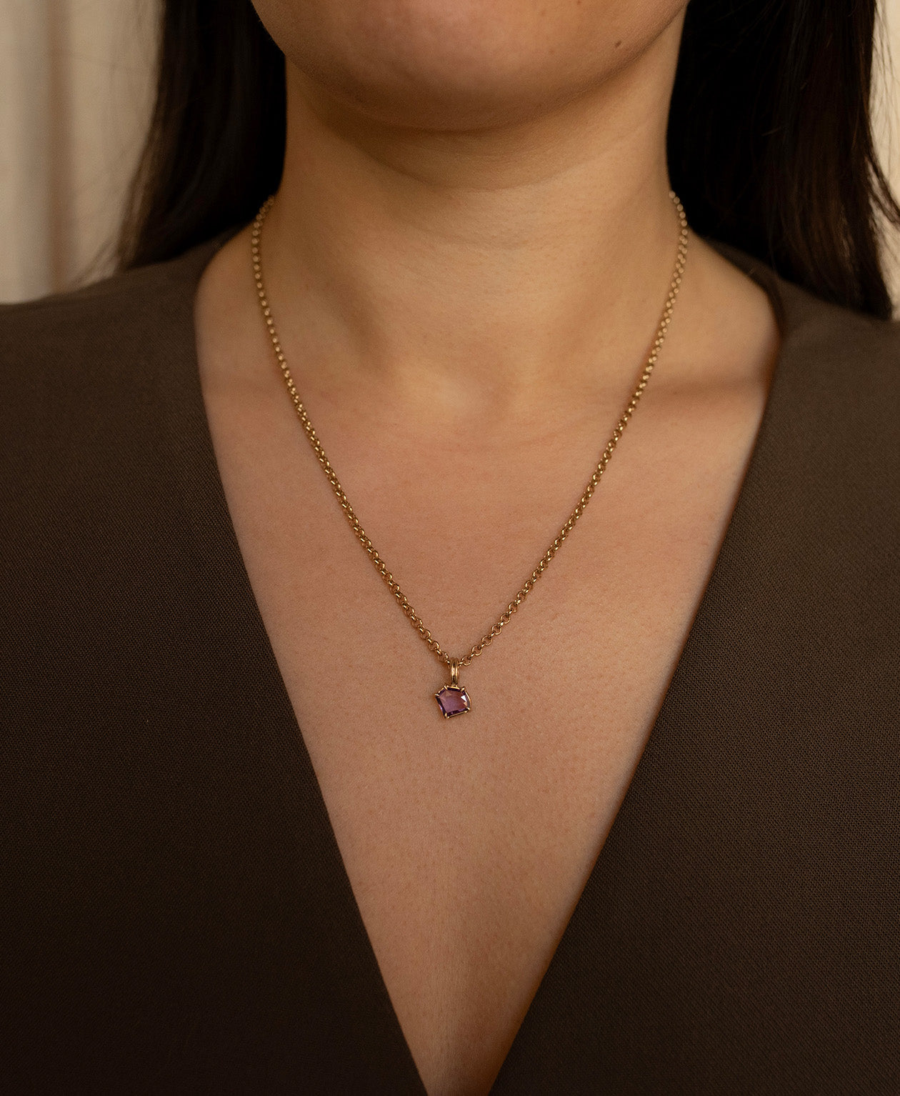Close up of the One of a Kind Charm 495 with a portrait cut purple sapphire worn by a model on a belcher chain.