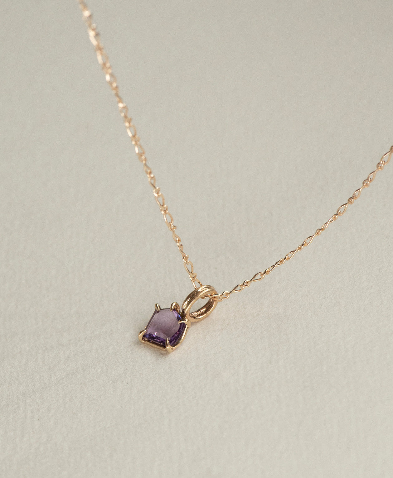 Close up of the One of a Kind Charm 495 with a portrait cut purple sapphire on a figaro chain.
