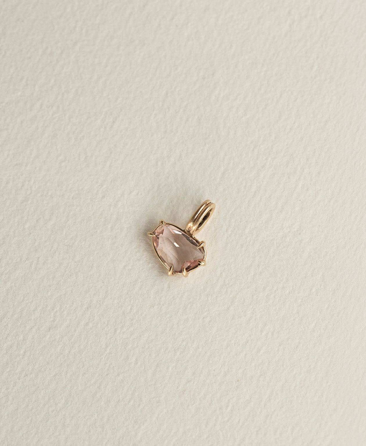 Angled view of the One of a Kind Charm 496 in 9k Yellow Gold with a pink sapphire.