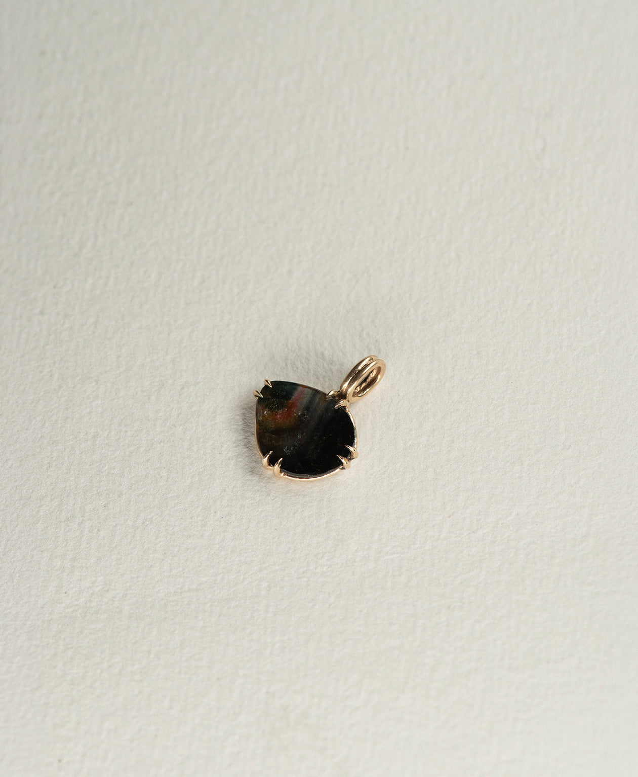 Angled view of the One of a Kind Charm 498 in 9k Yellow Gold with a rose cut black Tourmaline.