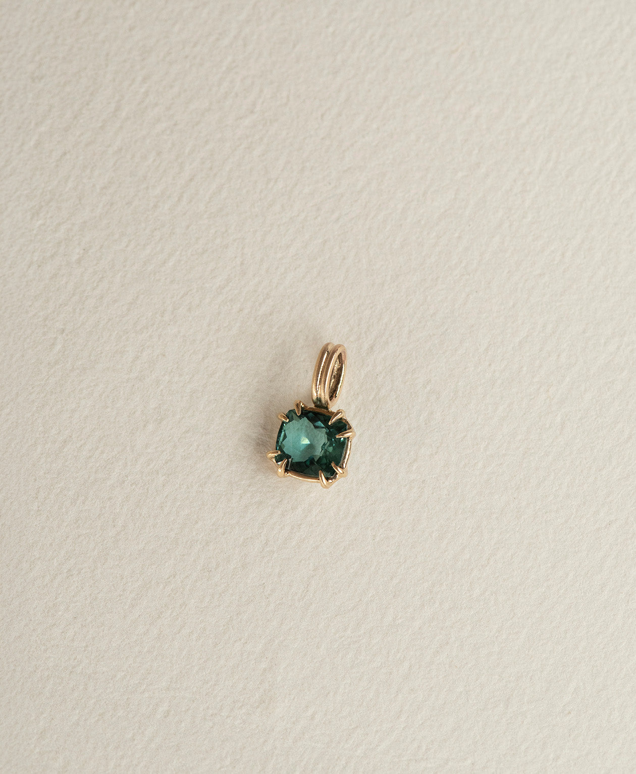 Angled view of the One of a Kind Charm 501 in 9k Yellow Gold with a teal cushion cut Tourmaline.