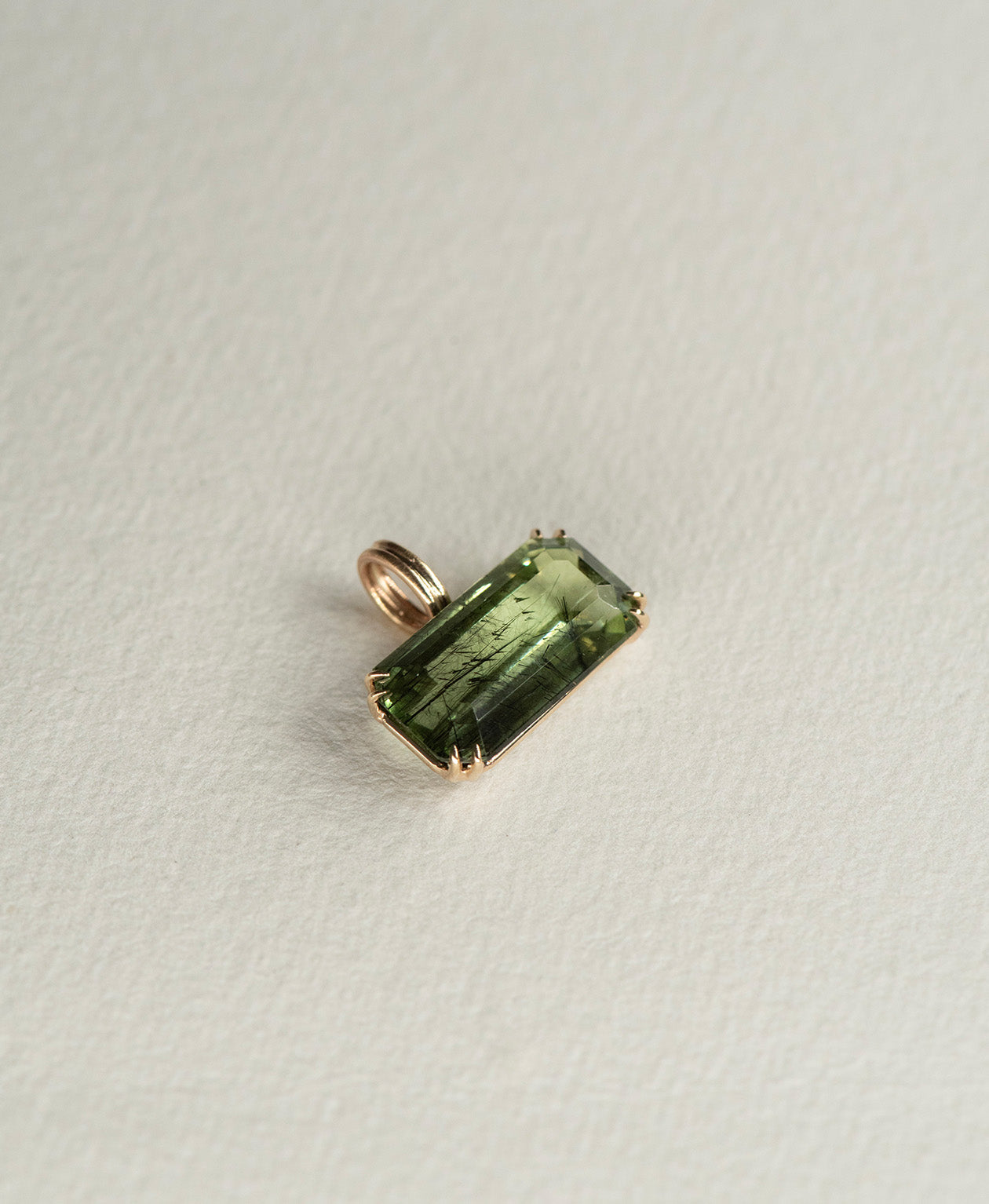 Angled view of the One of a Kind Charm 502 in 9k Yellow Gold with a deep green emerald cut Peridot.