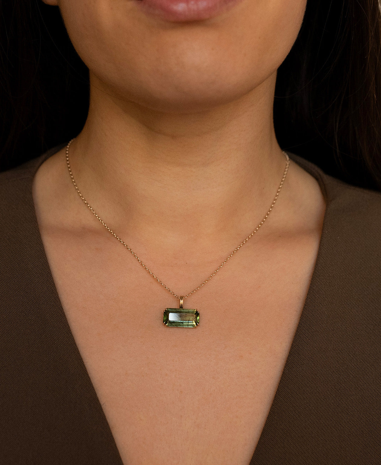 Close up of the One of a Kind Charm 502 with a deep green emerald cut Peridot worn by a model on a fine belcher chain.