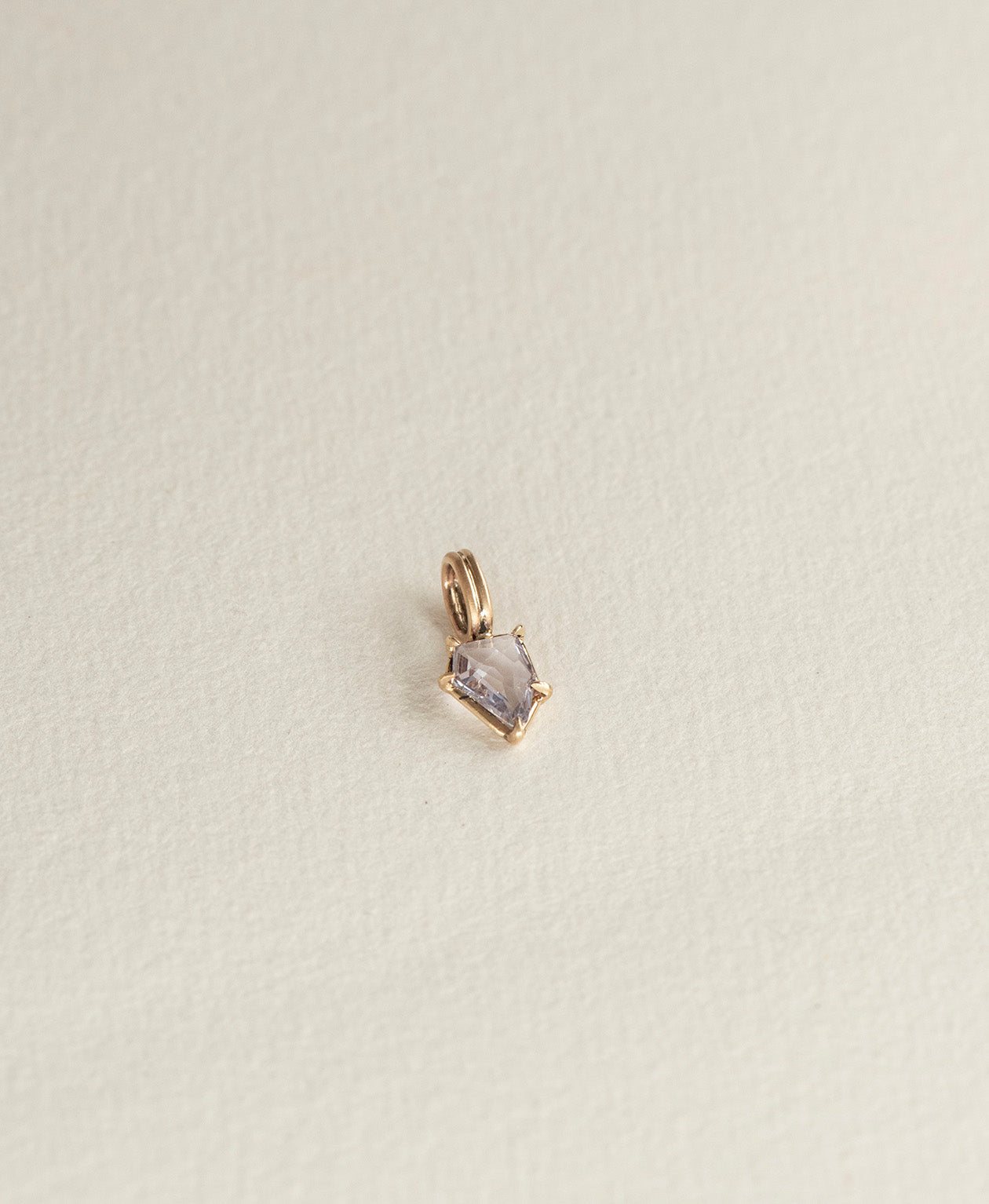 Angled view of the One of a Kind Charm 506 in 9k Yellow Gold with a light blue portrait cut Sapphire.