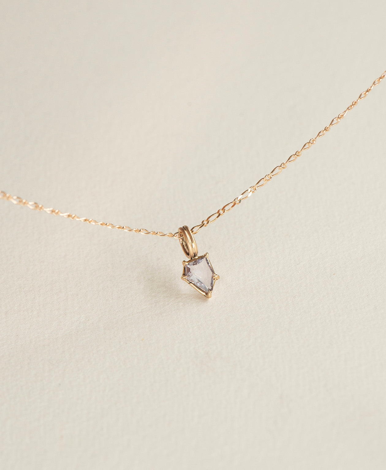 Close up of the One of a Kind Charm 506 with a light blue portrait cut Sapphire on a figaro chain.