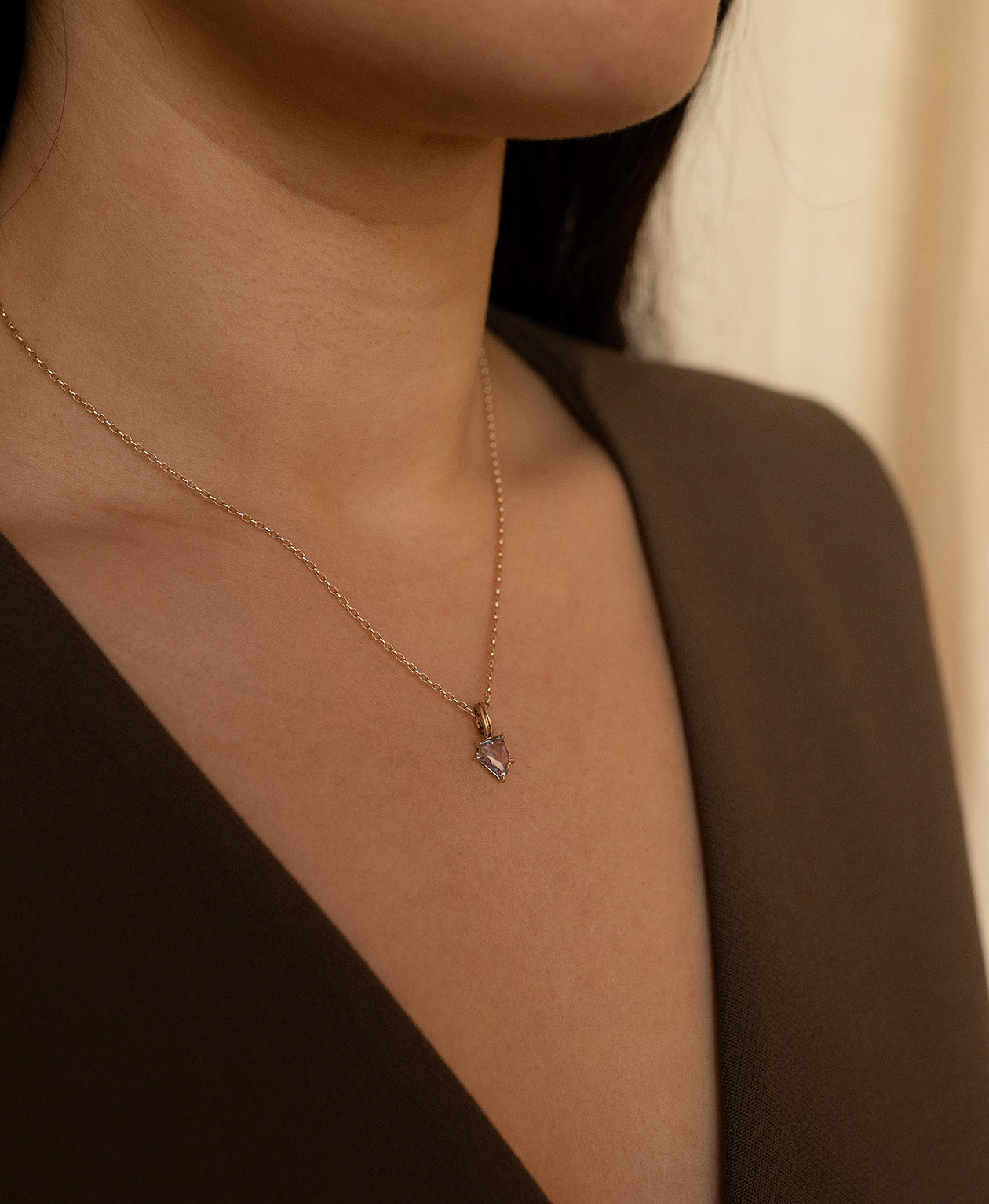 Close up of the One of a Kind Charm 506 with a light blue portrait cut Sapphire worn by a model on a fine belcher chain.