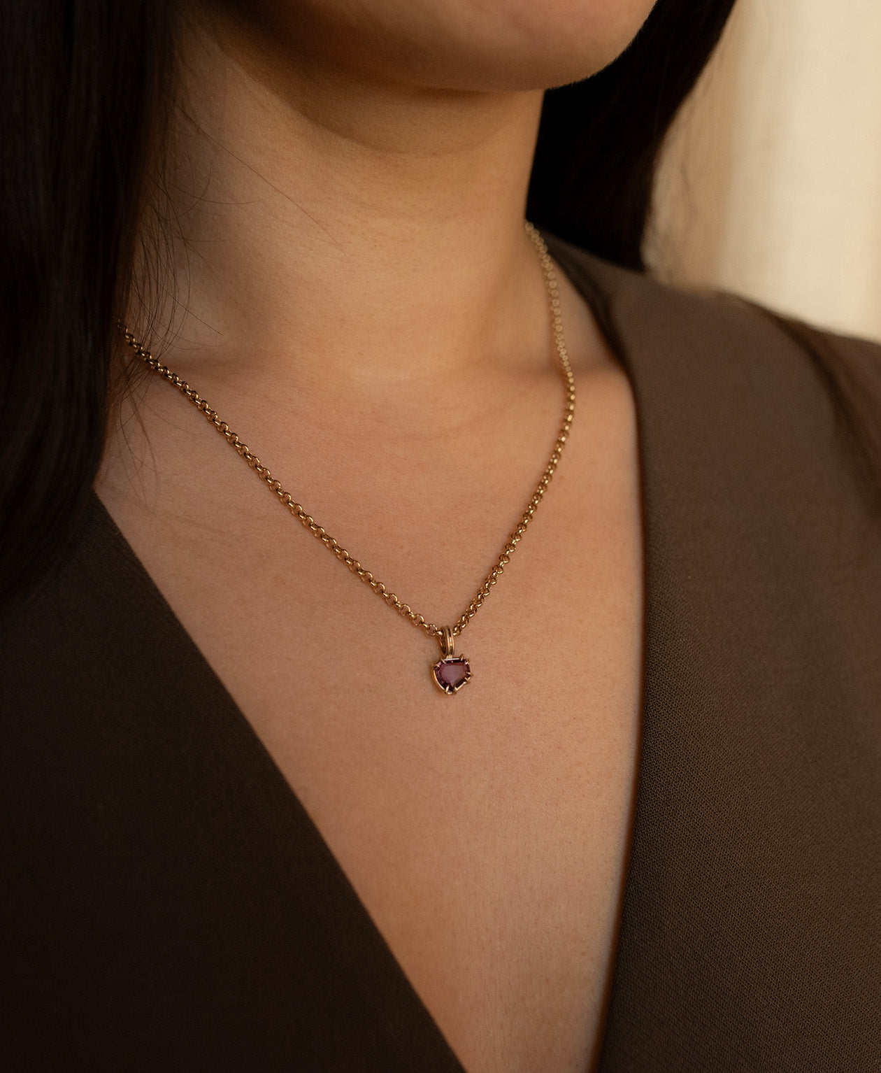 Close up of the One of a Kind Charm 507 with a deep purple portrait cut Sapphire worn by a model on a belcher chain.