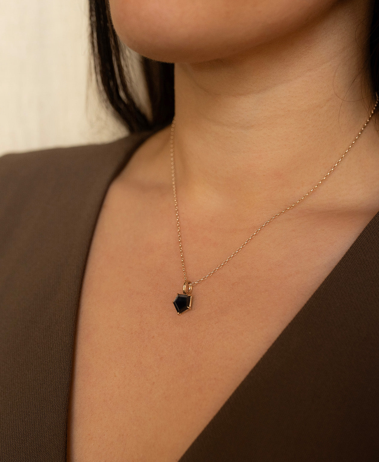 One of a Kind Charm 508 with a deep blue portrait cut Sapphire worn by a model on a fine belcher chain.