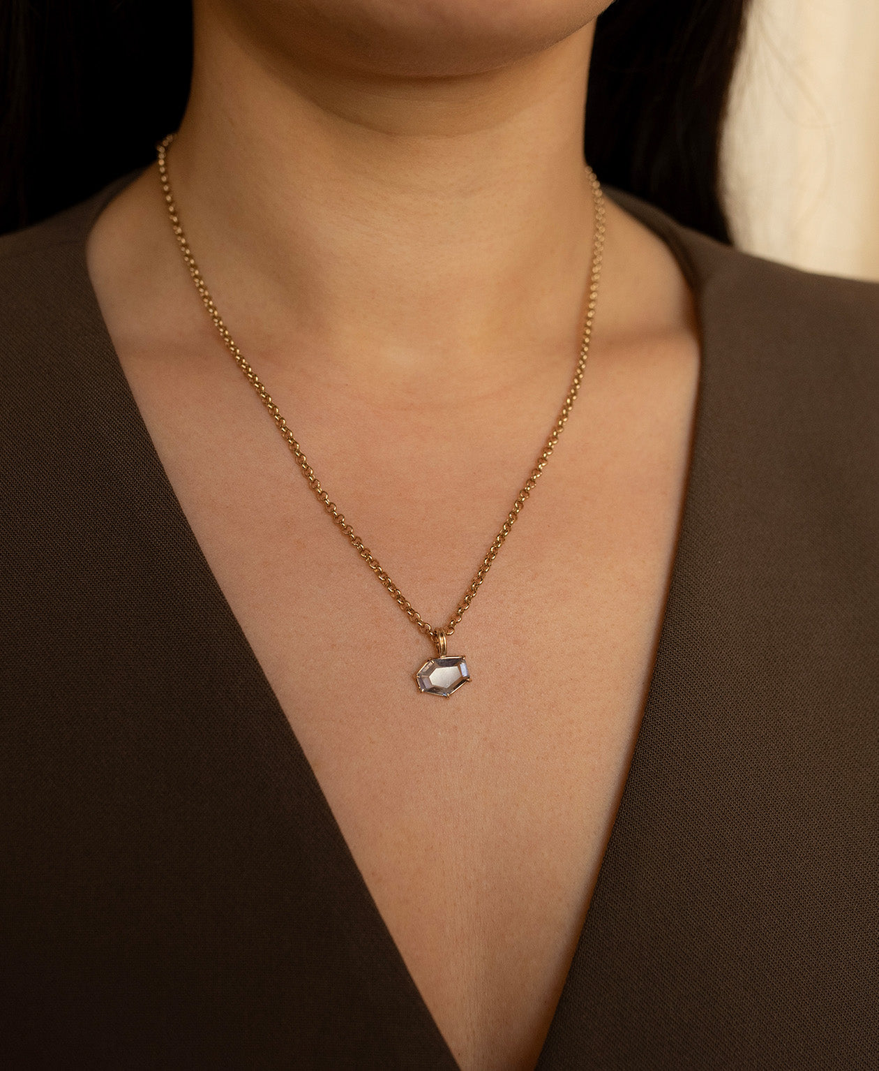 Close up of the One of a Kind Charm 509 with a lilac hexagonal cut Sapphire worn by a model on a belcher chain.