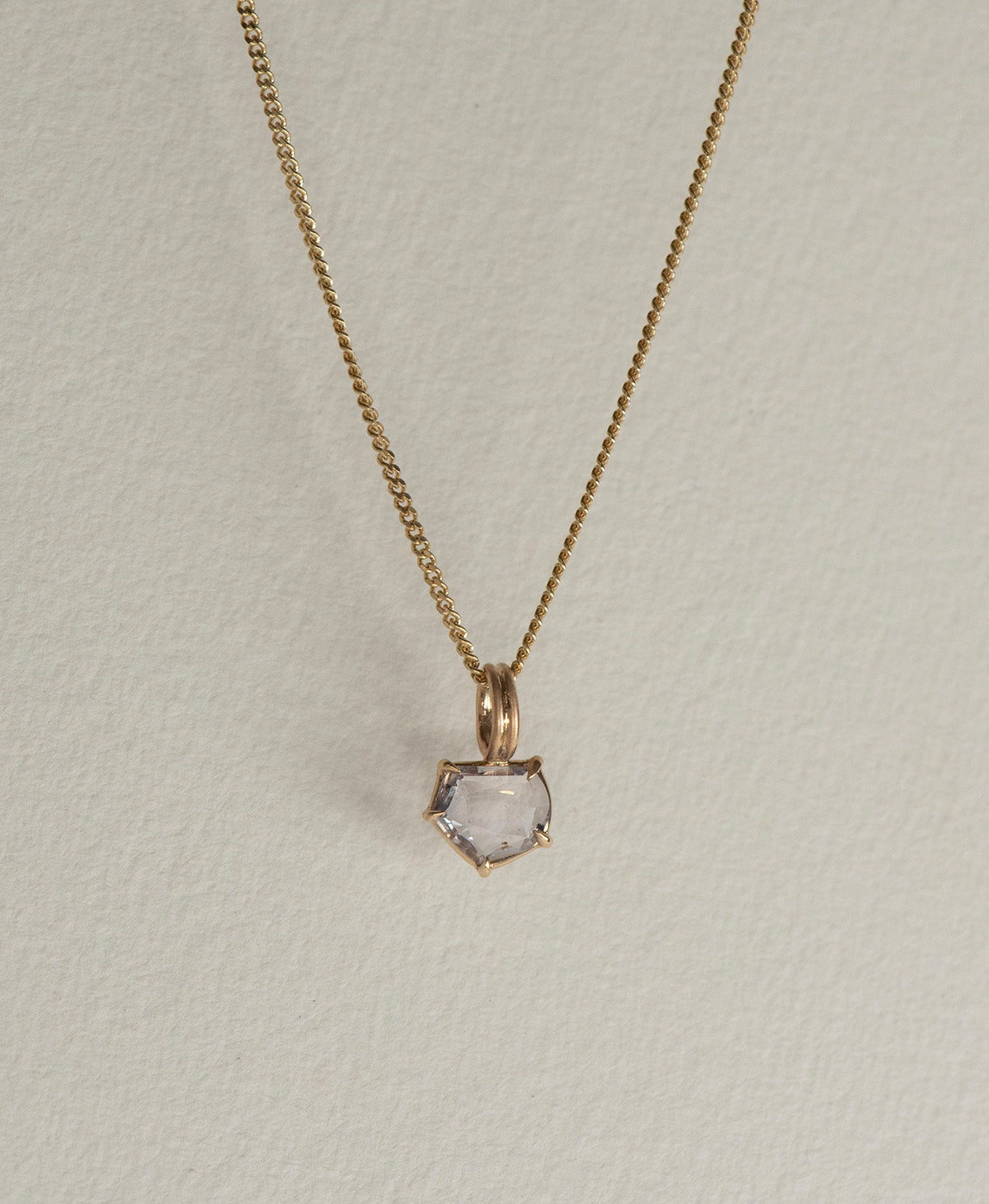 Close up of the One of a Kind Charm 511 with a lilac portrait cut Sapphire on a curb chain.