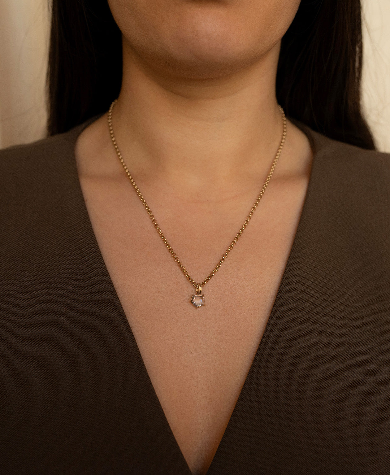Close up of the One of a Kind Charm 511 with a lilac portrait cut Sapphire worn by a model on a fine belcher chain.