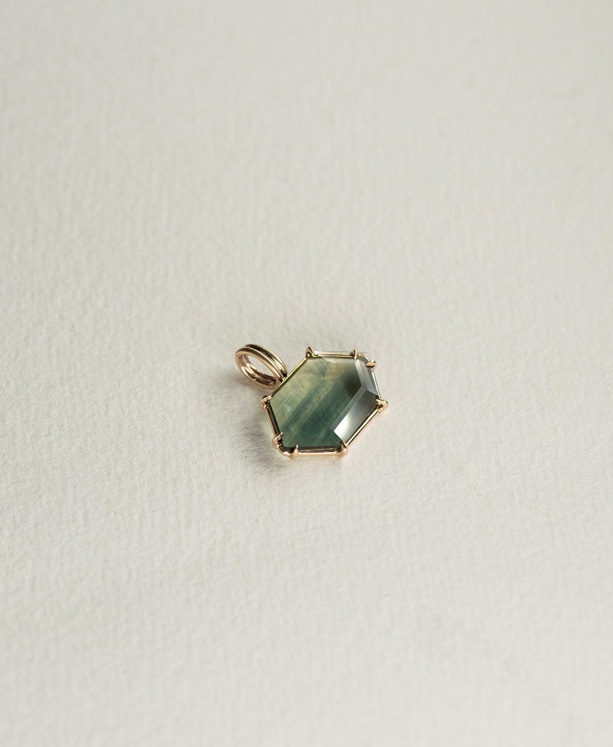 Angled view of the One of a Kind Charm 512 in 9k Yellow Gold with a light teal portrait cut Australian Sapphire.