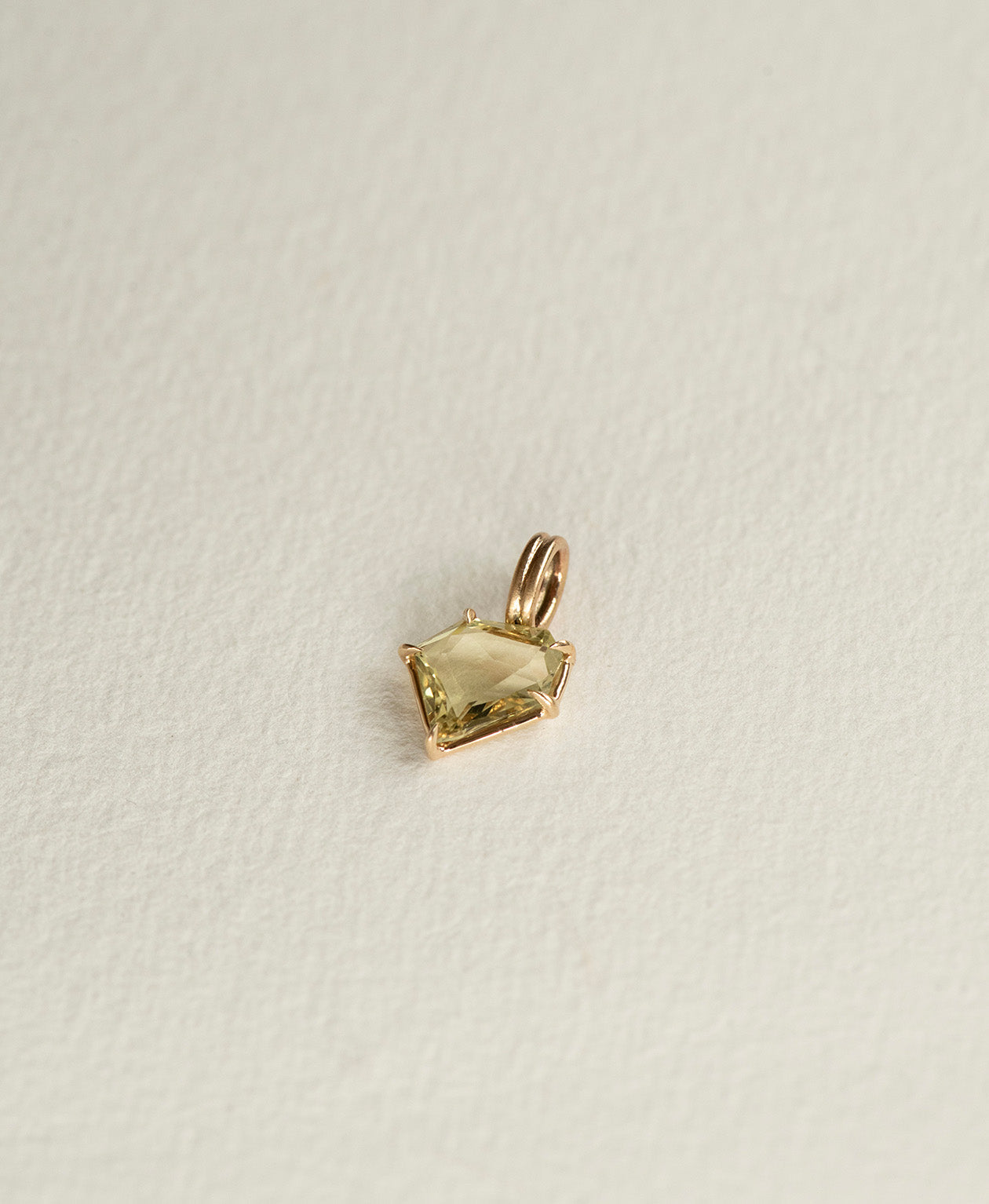Angled view of the One of a Kind Charm 514 in 9k Yellow Gold with a light yellow portrait cut Sapphire.