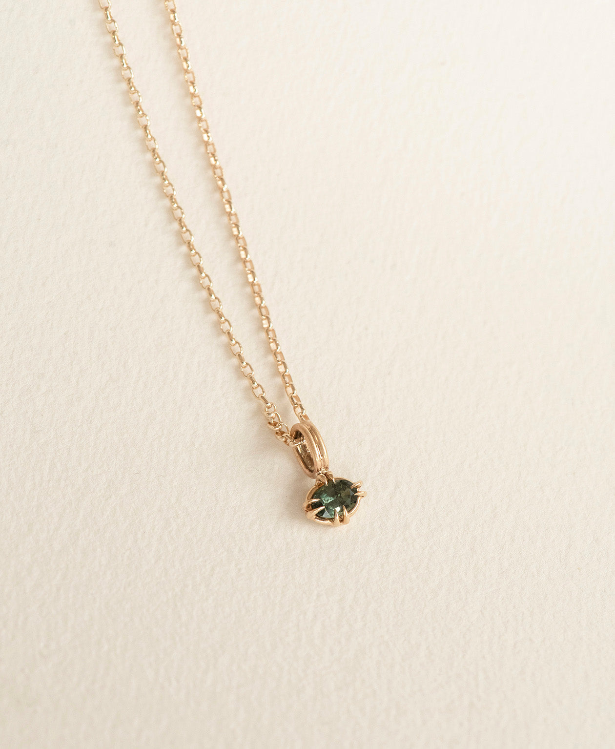 Close up of the One of a Kind Charm 515 with a forest green oval cut Sapphire on a fine belcher chain.