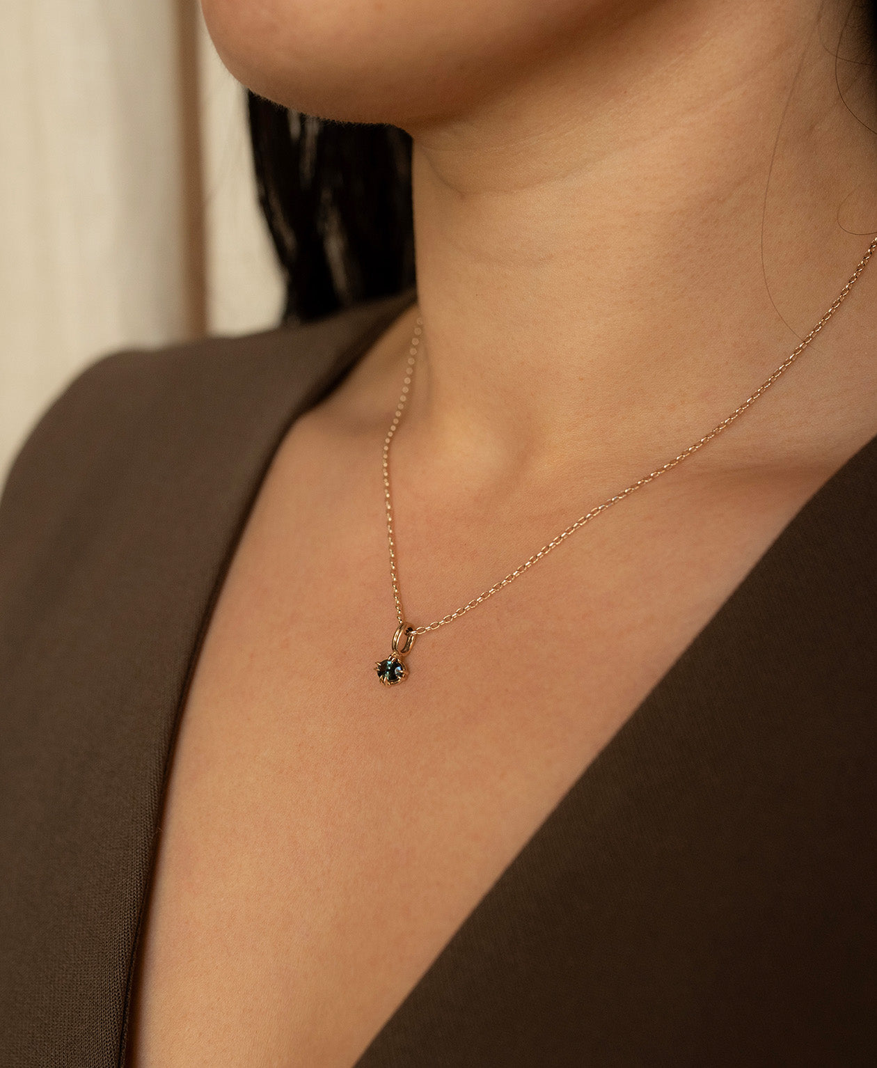 One of a Kind Charm 515 with a forest green oval cut Sapphire worn by a model on a fine belcher chain.