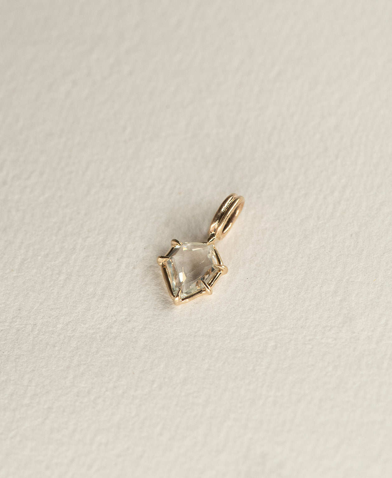 Side angle view of the One of a Kind Charm 516 in 9k Yellow Gold with a white portrait cut Sapphire.