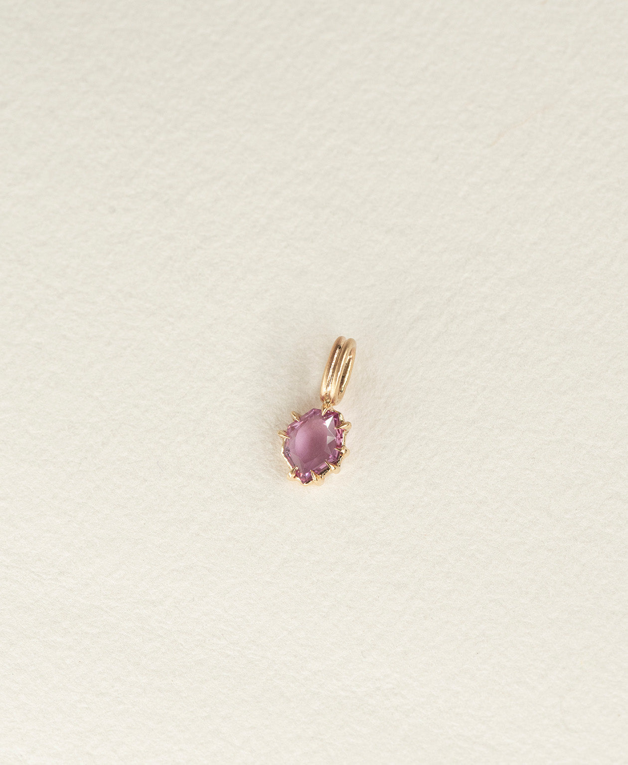Angled view of the One of a Kind Charm 517 in 9k Yellow Gold with a pale purple portrait cut Sapphire.