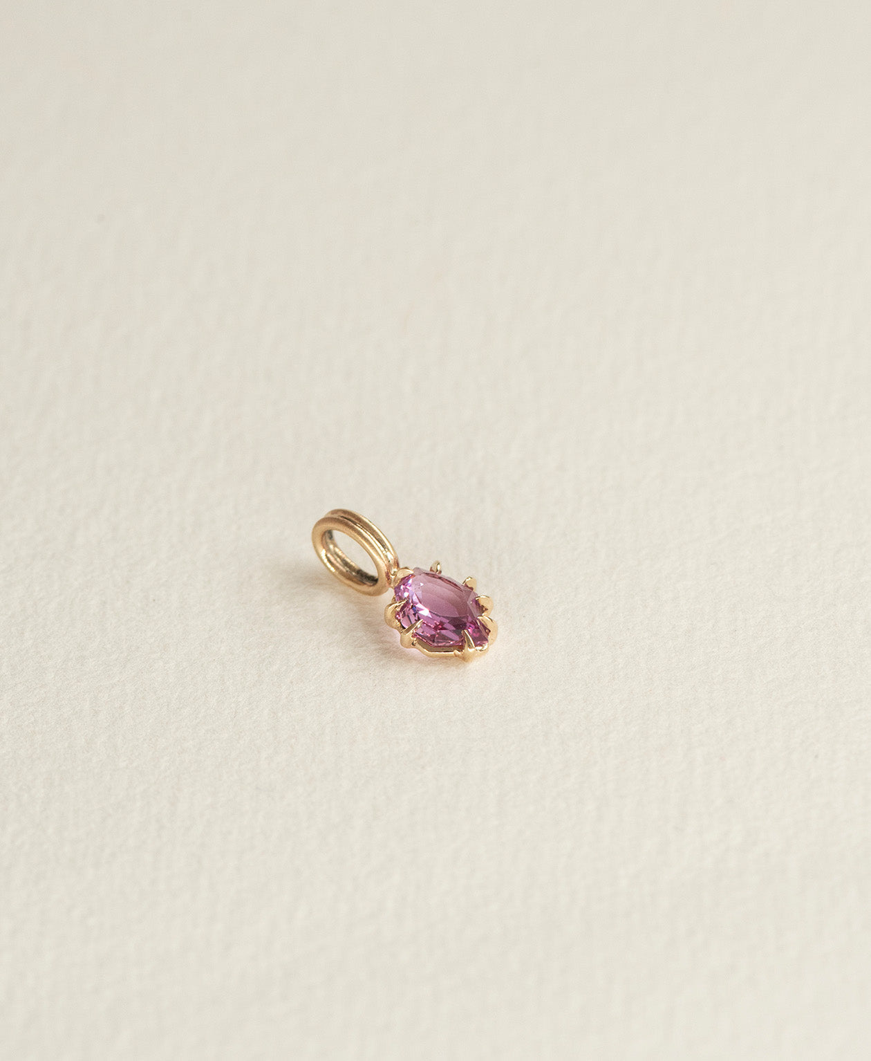 Side angle view of the One of a Kind Charm 517 in 9k Yellow Gold with a pale purple portrait cut Sapphire.