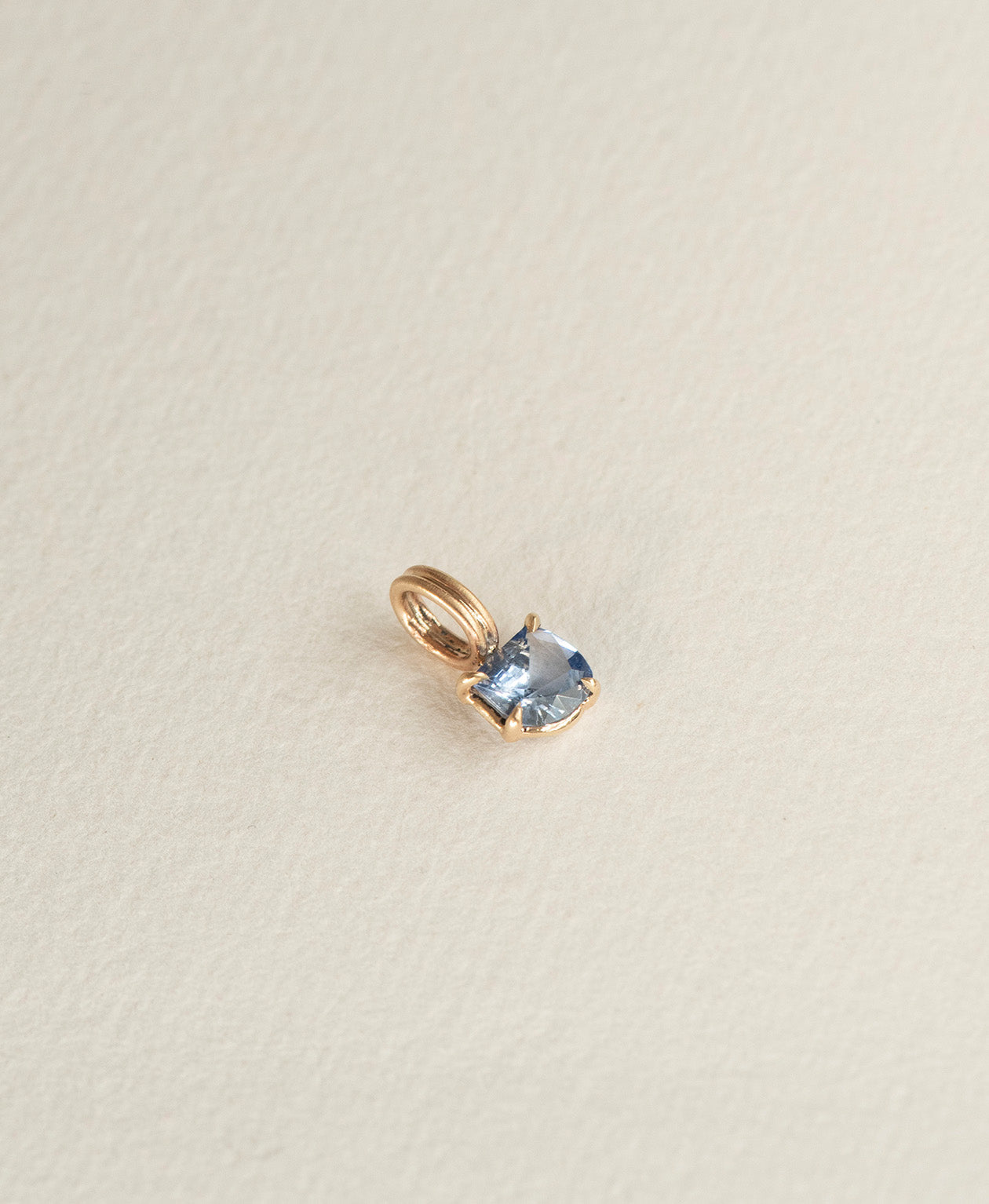 Angled view of the One of a Kind Charm 518 in 9k Yellow Gold with a blue fancy cut Sapphire.