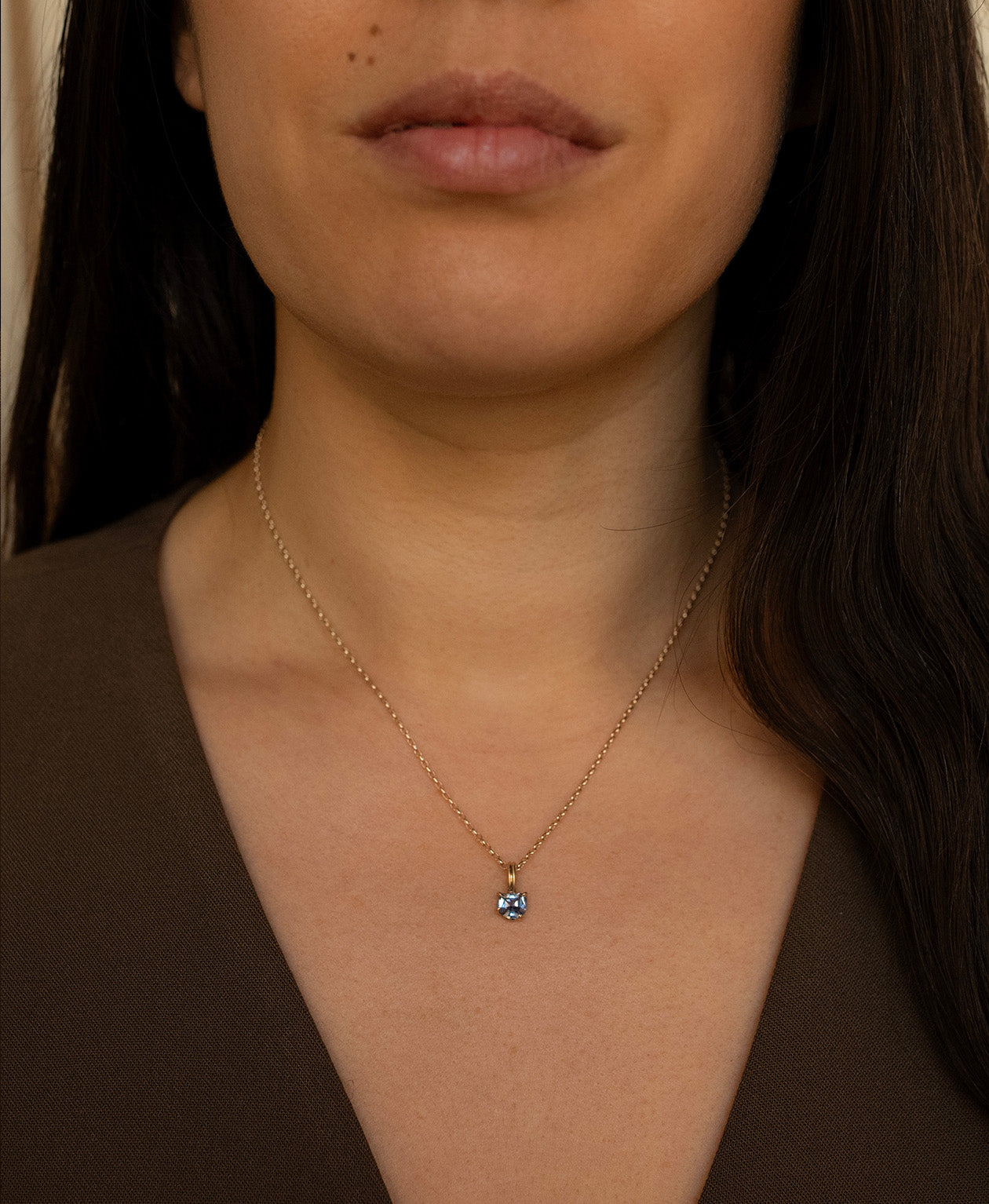 Close up of the One of a Kind Charm 518 with a blue fancy cut Sapphire worn by a model on a fine belcher chain.