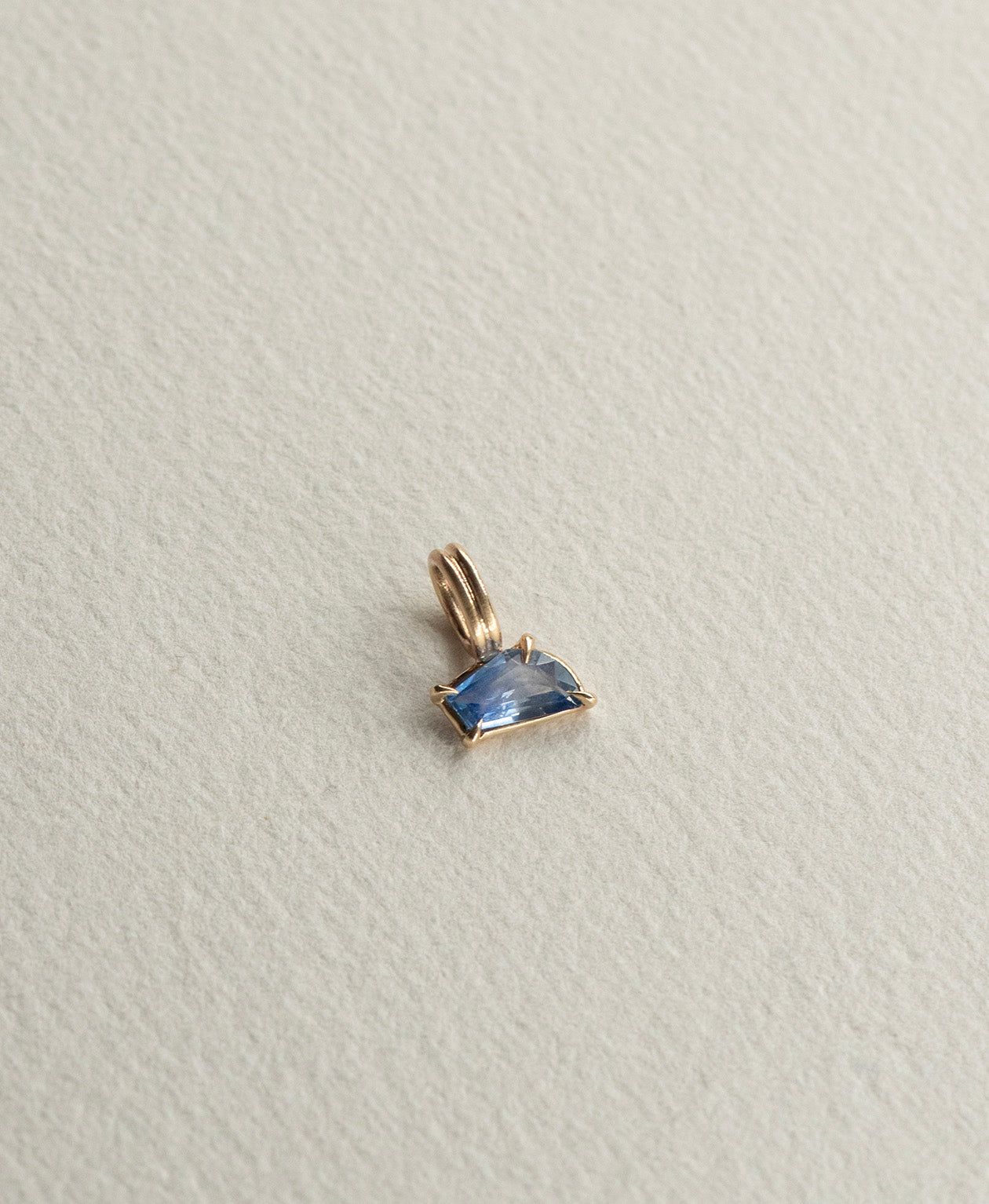 Angled view of the One of a Kind Charm 519 in 9k Yellow Gold with a blue fancy cut Sapphire.