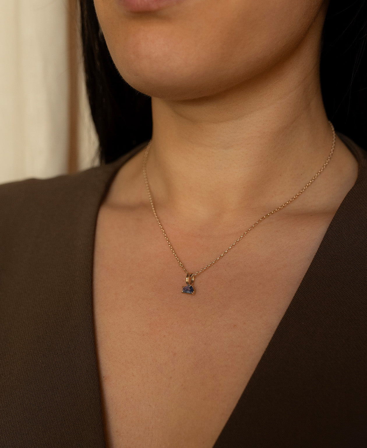 Close up of the One of a Kind Charm 519 with a blue fancy cut Sapphire worn by a model on a fine belcher chain.