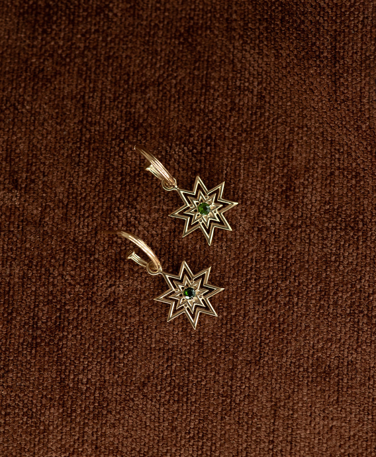 The Nora Hoops, featuring an eight pointed star suspended from a hoop, displayed on a textured brown fabric background.