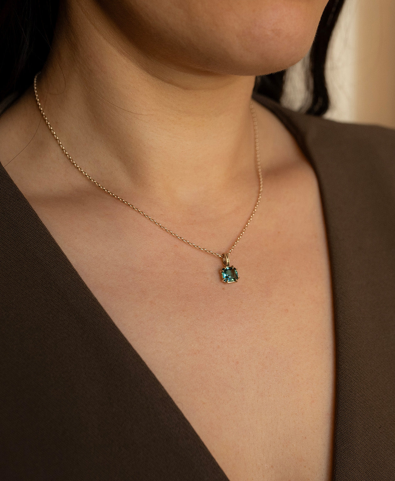 Close up of the One of a Kind Charm 501 with a teal cushion cut Tourmaline worn by a model on a belcher chain. 