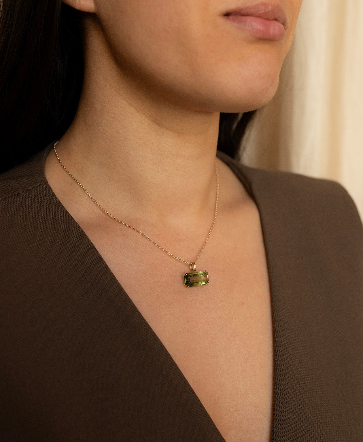 One of a Kind Charm 502 with a deep green emerald cut Peridot worn by a model on a fine belcher chain.