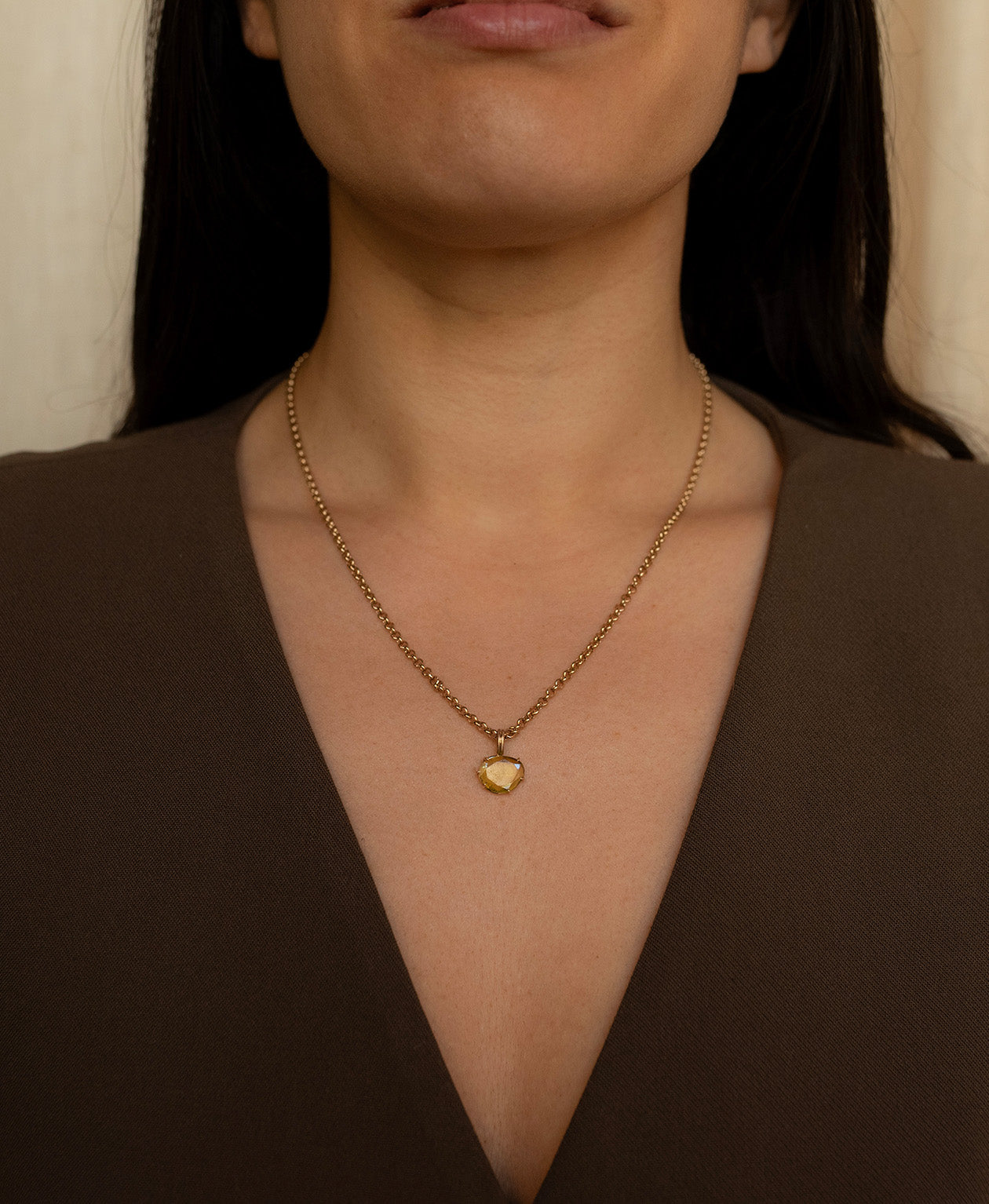 Close up of the One of a Kind Charm 503 with a rose cut green Tourmaline worn by a model on a fine belcher chain. 