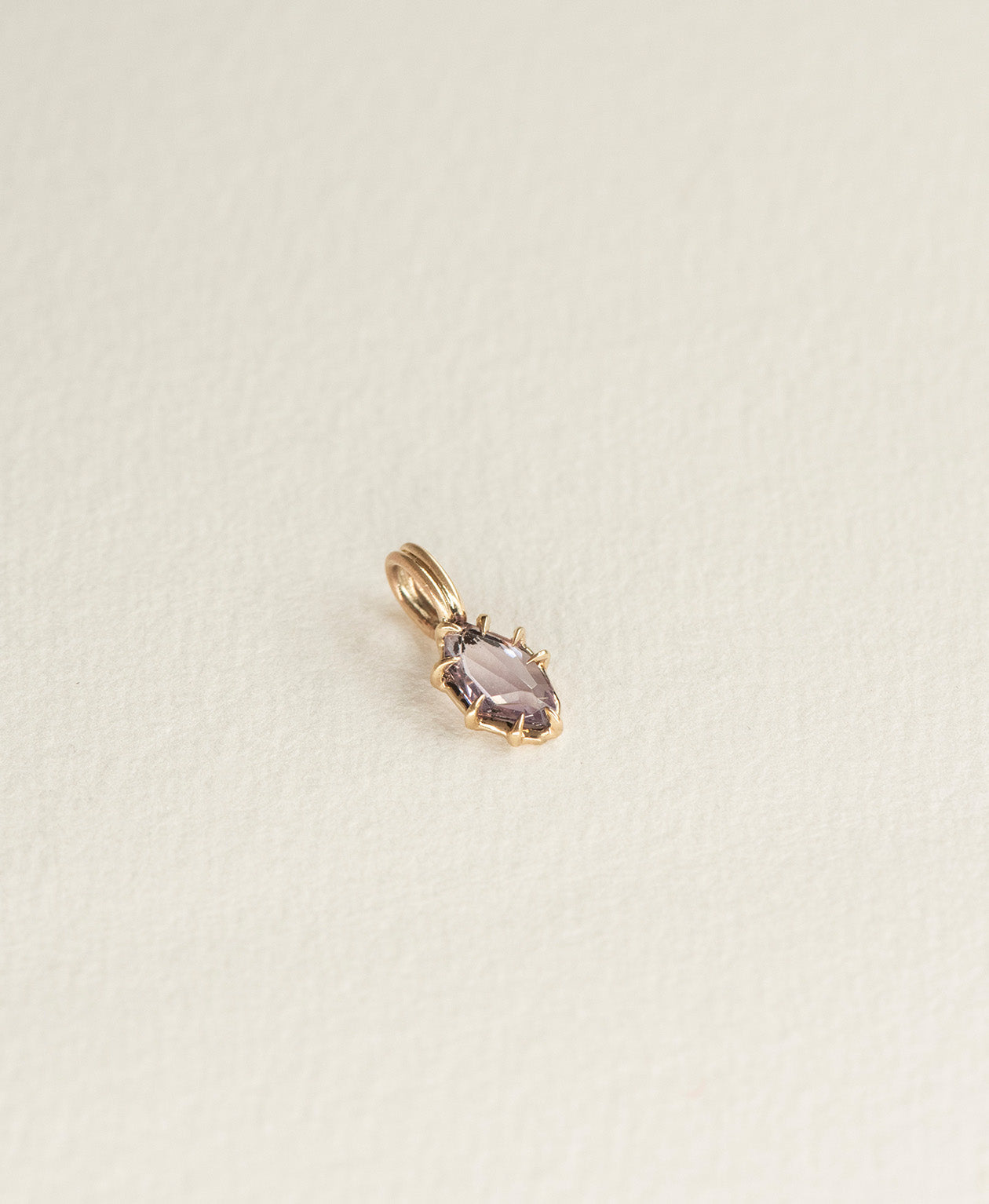 Angled view of the One of a Kind Charm 510 in 9k Yellow Gold with a purple portrait cut Sapphire.
