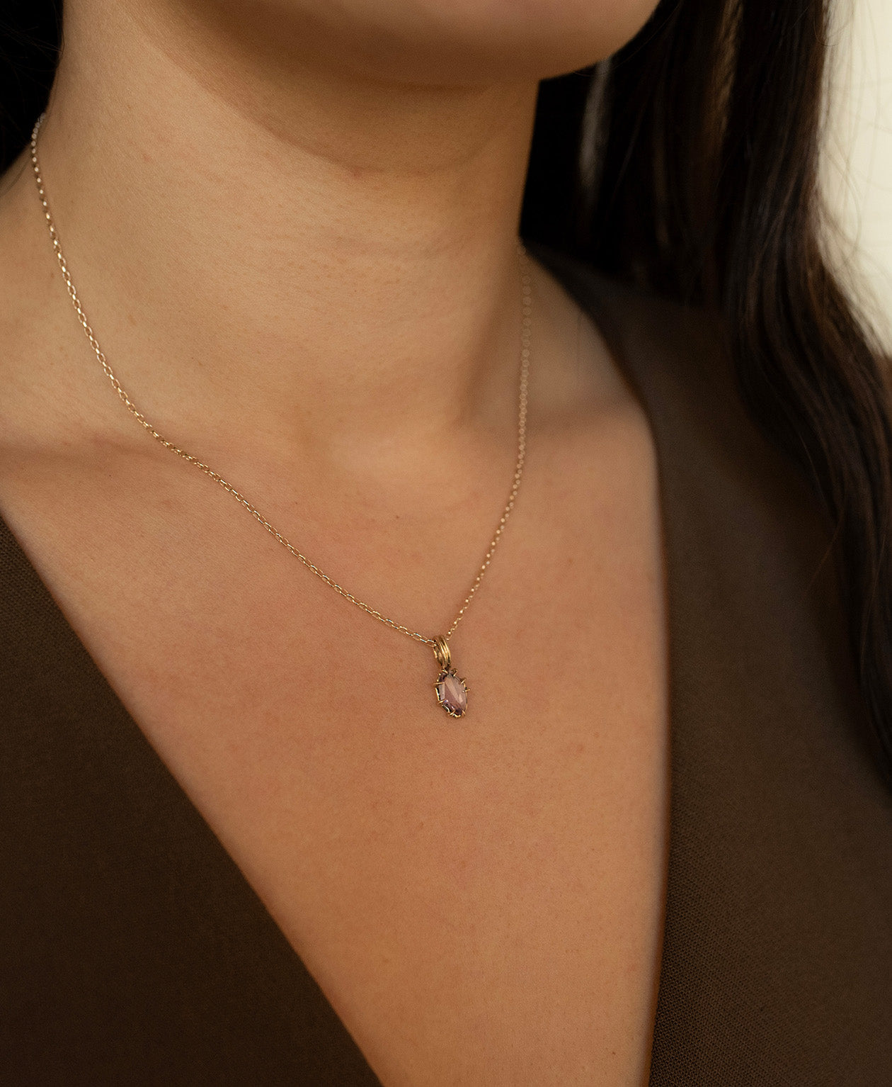 Close up of the One of a Kind Charm 510 with a purple portrait cut Sapphire worn by a model on a fine belcher chain.