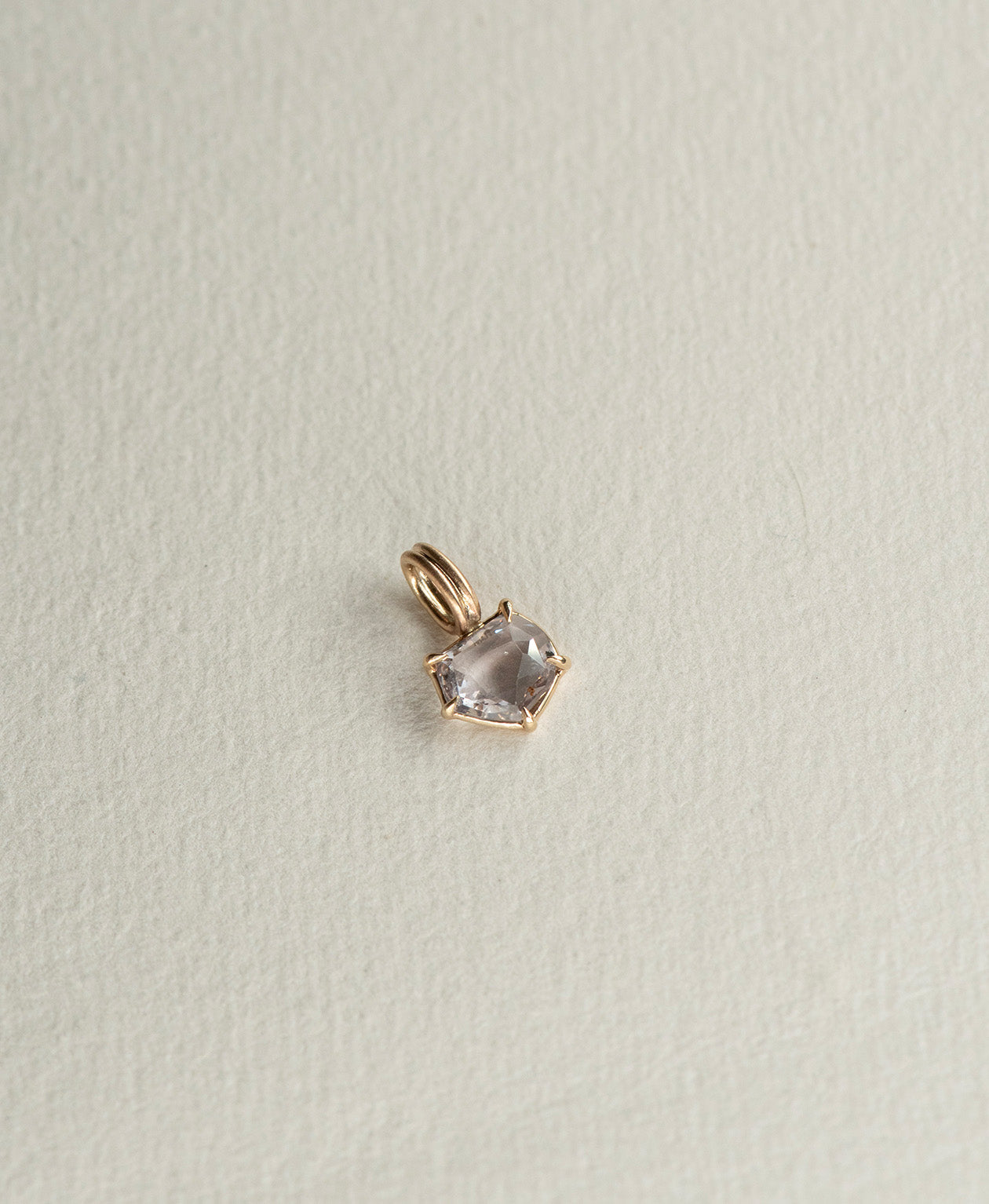 Angled view of the One of a Kind Charm 511 in 9k Yellow Gold with a lilac portrait cut Sapphire.