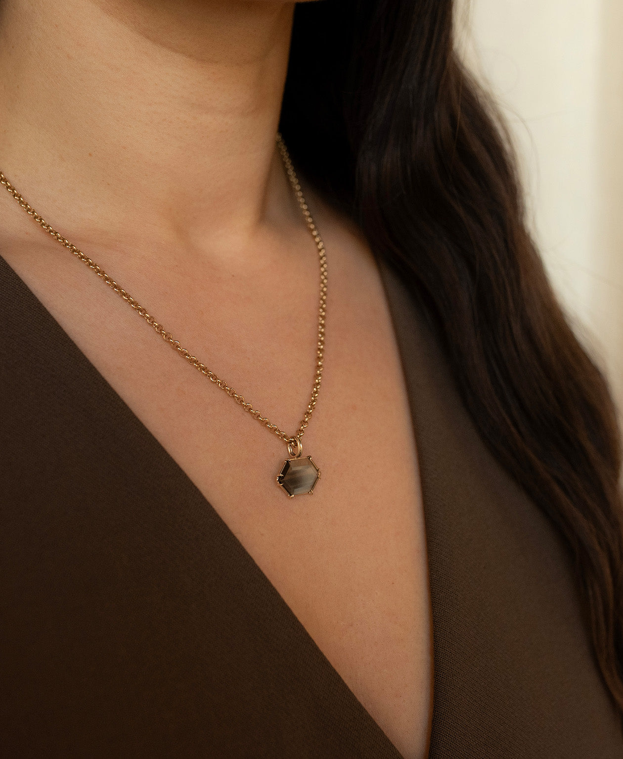 Close up of the One of a Kind Charm 512 with a light teal portrait cut Australian Sapphire worn by a model on a belcher chain. 