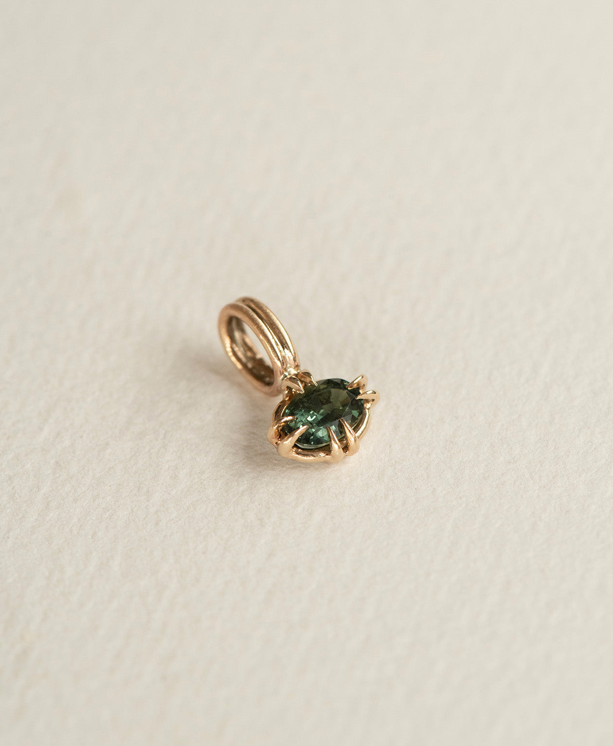Angled view of the One of a Kind Charm 515 in 9k Yellow Gold with a forest green oval cut Sapphire.