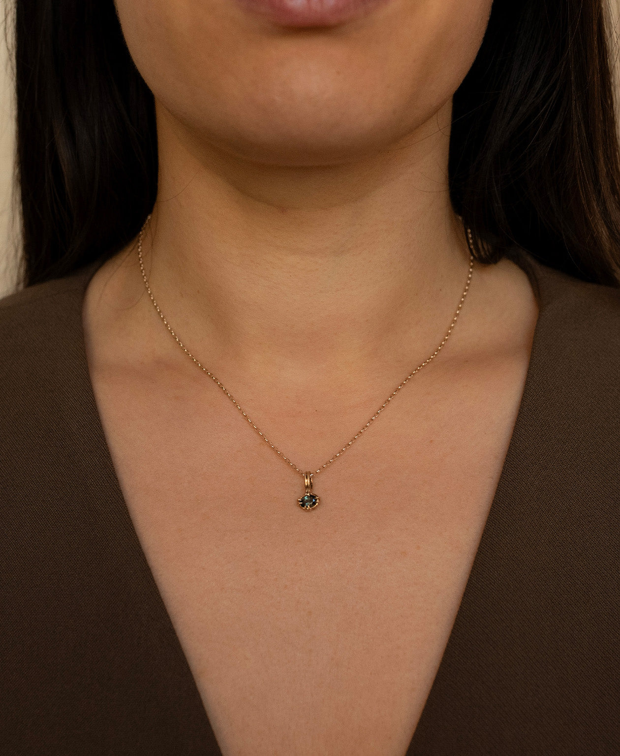 Close up of the One of a Kind Charm 515 with a forest green oval cut Sapphire worn by a model on a fine belcher chain. 