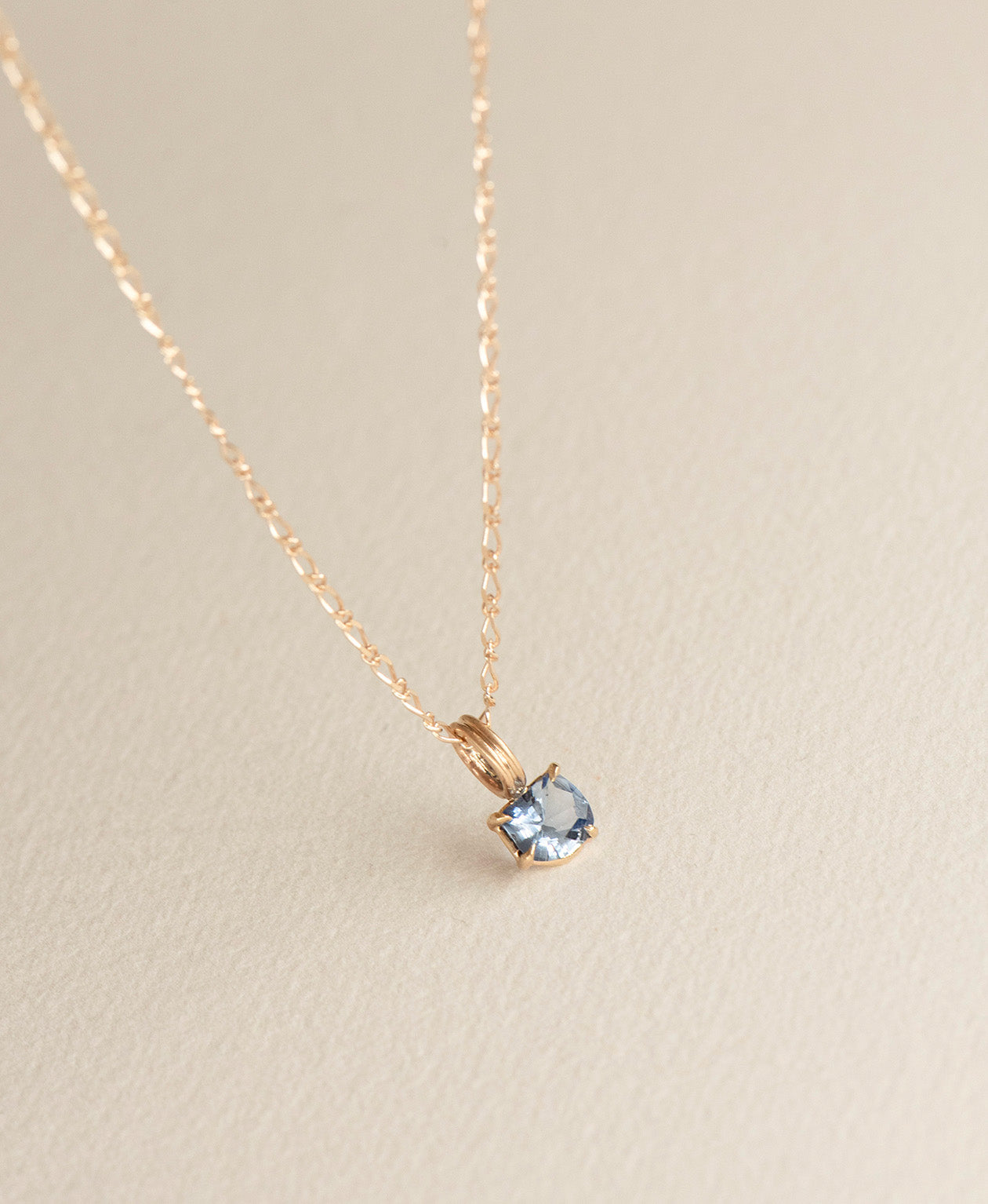 Close up of the One of a Kind Charm 518 with a blue fancy cut Sapphire on a fine figaro chain.