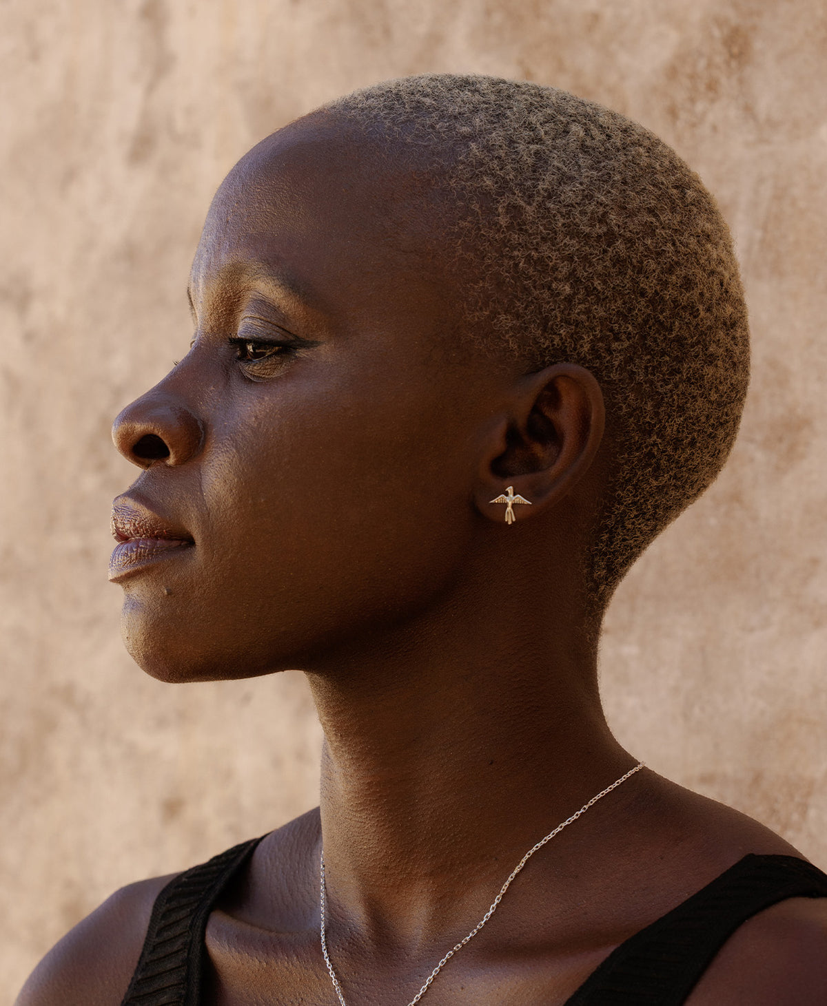 A profile of a person wearing the silver Bird of a Feather Studs, featuring a bird stud earrings with detailed feather and wing textures.